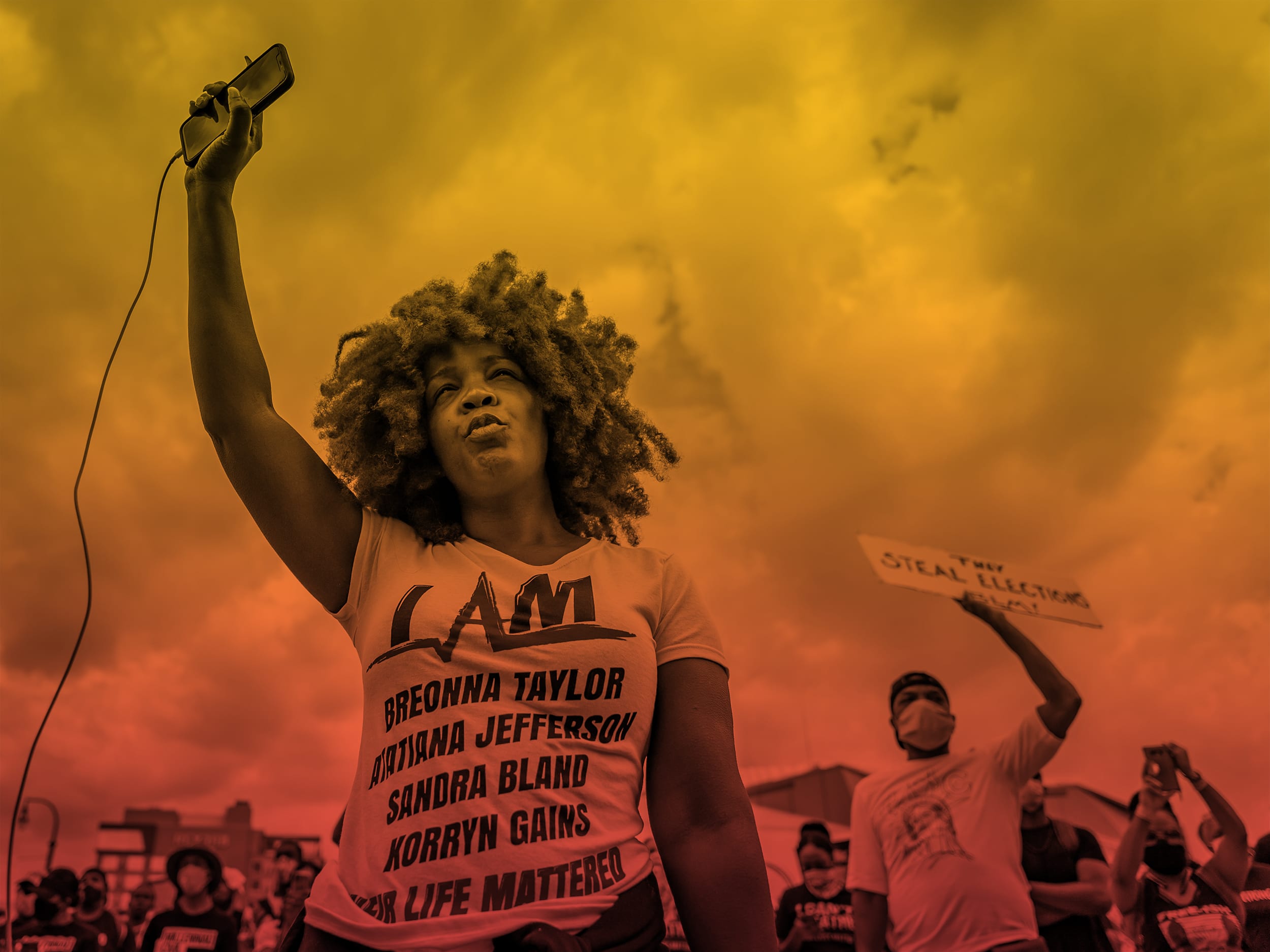 Woman raising a phone in the air during a protest